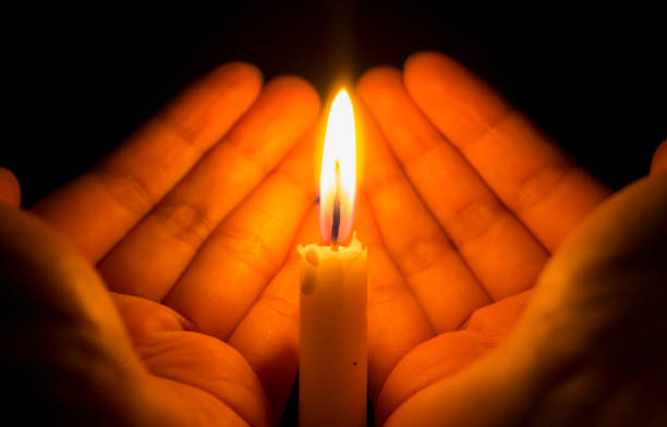 istock Hand covering burning candle in the dark room. 1285426686
