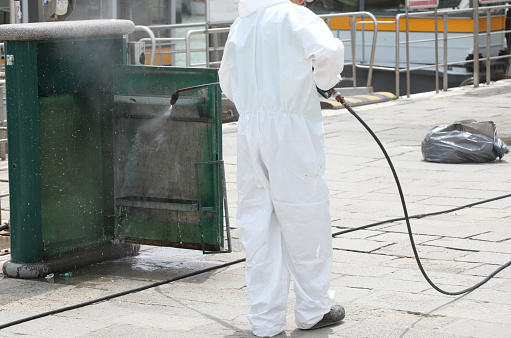sanitation of the waste basket with the staff wearing a protective suit to protect themselves from the coronavirus