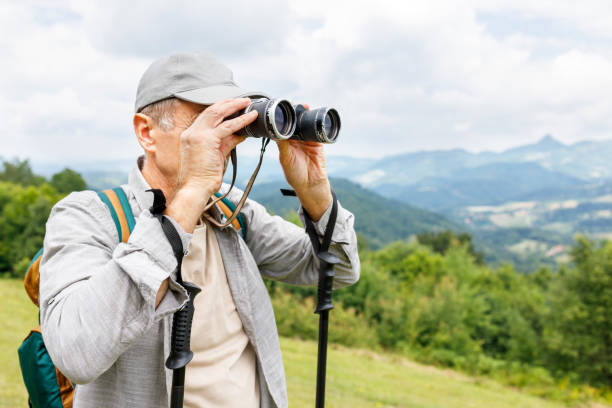 istock Senior man on mountain with binoculars 1285429323
