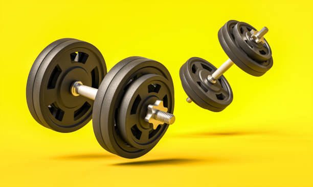 istock classic gym dumbbells on a yellow background. 1285429641