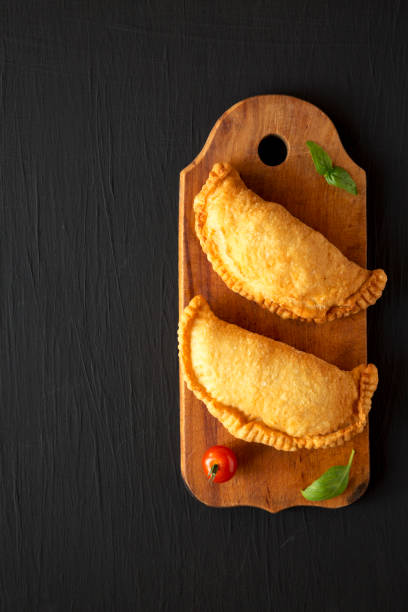 istock Homemade Deep Fried Italian Panzerotti Calzone on a rustic wooden board on a black surface, top view. Flat lay, overhead, from above. Copy space. 1285431301