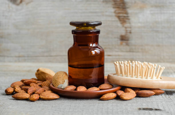 botella de farmacia con aceite de almendras y cepillo de pelo de madera. concepto de cuidado natural del cabello. antiguo fondo de madera. almendras de cerca. copiar espacio - ayurveda massaging spa treatment massage oil fotografías e imágenes de stock