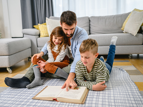 Father reading a book with their kids.