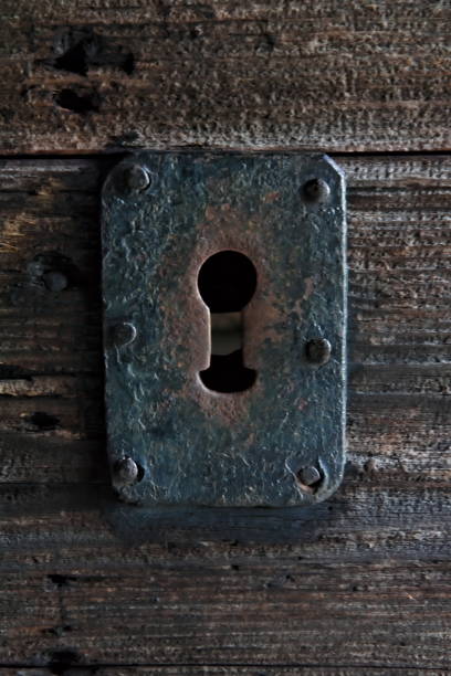 istock Rusted antique keyhole on a weathered old wooden doorframe. 1285445558
