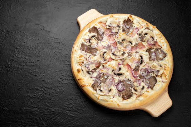 istock BBQ pizza on a black background, on a cream base in combination with mozzarella, veal BBQ, bacon, mushrooms, red pickled onions 1285446573
