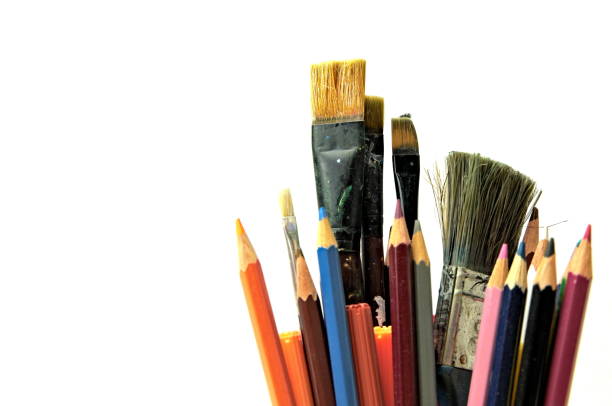 Used paint brushes and pencils sitting in a jar and isolated on white background