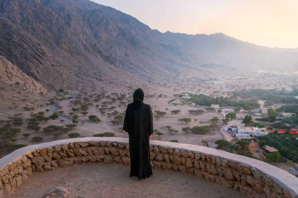 Woman in abaya visiting middle eastern fortress in the desert at sunset Woman in hijab visiting middle eastern fortress in the desert of United Arab Emirates at sunset jebel hafeet stock pictures, royalty-free photos & images