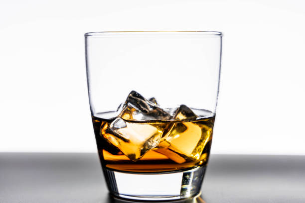 istock Glass of whiskey with ice cubes on white background 1285448246