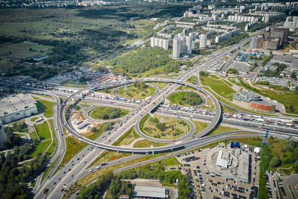 Big clover intersection with long curve ways and exits. View from far and high altitude. Big metropolis traffic life. Top down aerial view. Sunlight. Green plants, forest around and residential areas and districts with buildings on the horizon. gran intersección de trébol con largos caminos y salidas curvas. vista desde lejos y a gran altitud. gran metrópolis de la vida del tráfico. vista aérea de arriba hacia abajo. luz solar. plantas verdes, bosques alrededor y zonas residenciales y distri