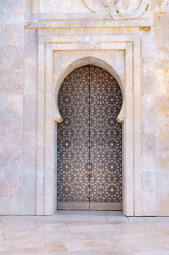 Massive entrance doors of Hassan II Mosque, decorated with traditional Moroccan patterns and an arch.