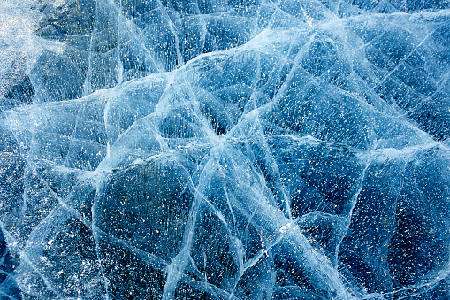 Beautiful blue ice of Lake Baikal with cracks. Natural cold background of ice.