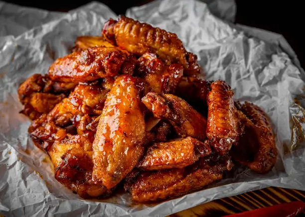 Photo of fried chicken wings with sweet chili sauce on white paper