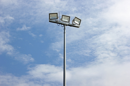 Spotlight pole, Power poles and sport light with blue sky and clouds background.
