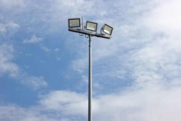 polo de destaque, postes de energia e luz esportiva com céu azul e fundo de nuvens. - floodlight blue sky day - fotografias e filmes do acervo