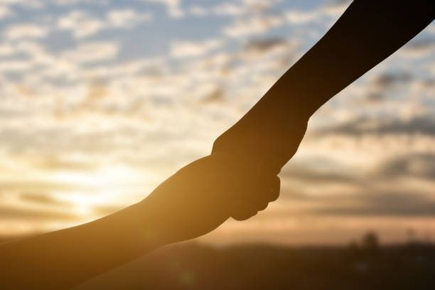 istock Silhouette of giving a help hand, hope and support each other over sunset background 1285466736