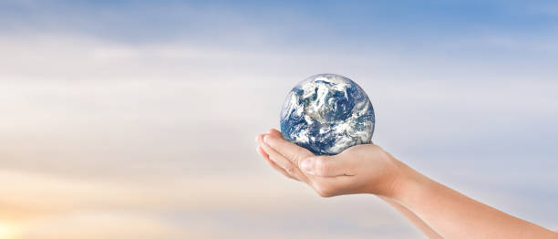 istock Globe in child hands over blue sky background. save of earth. 1285466870