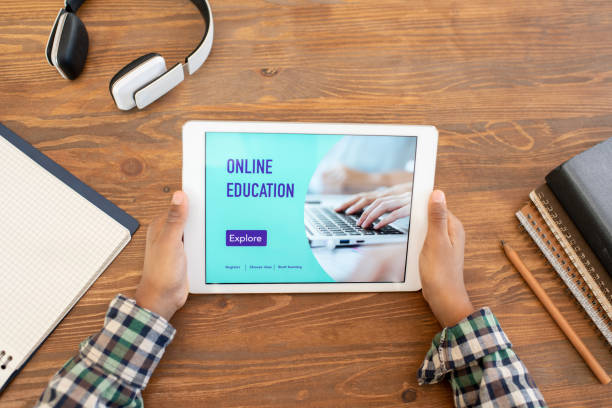 istock Top view of hands of elementary schoolboy watching online lesson by table 1285467092