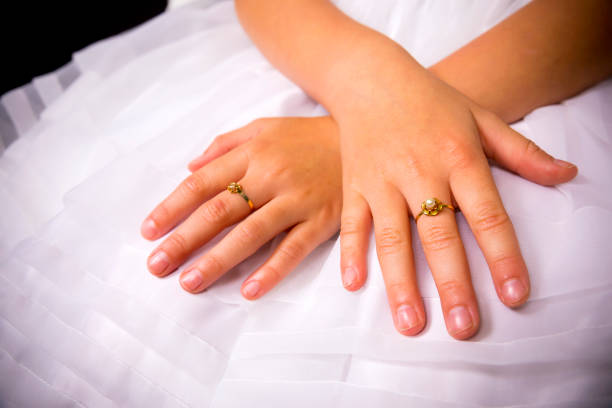 Studio shot on the black background of man's palm of hand passing white single rose flower to praying hands of woman.