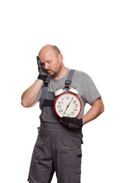 The car mechanic is holding a clock in his hand, he is tired and wants to take a nap The car mechanic is holding a clock in his hand, he is tired and wants to take a nap car portrait men expertise stock pictures, royalty-free photos & images