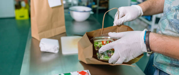 unkenntlich gemachter koch, der eine takeaway-bestellung verpackt - lunch take out food bag paper bag stock-fotos und bilder