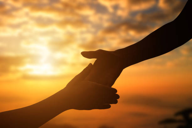 istock Silhouette of giving a helping hand, hope and support each other over sunset background. 1285474308