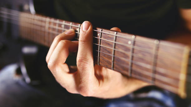 istock guitarist plays an electric guitar chord on a black background. Selective focus 1285478120