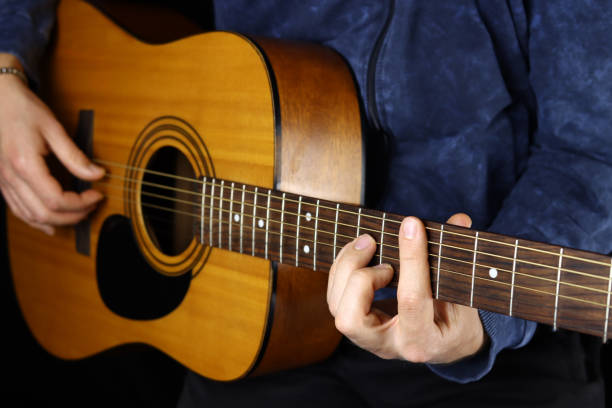 istock man playing acoustic guitar on a black background 1285478175