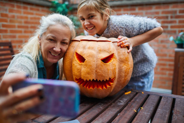 istock Mother And Her Daughter Making Selfie With Jack O' Lantern 1285479568