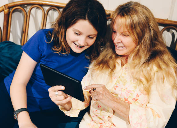 istock Woman in her sixties with child using a wirelss computer table at home, happy 1285479624