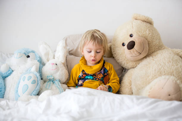 istock Beautiful child, toddler boy, reading book and playing with it, creative knowledge shot with book 1285479844