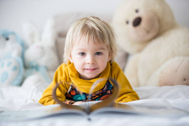 istock Beautiful child, toddler boy, reading book and playing with it, creative knowledge shot with book 1285480050