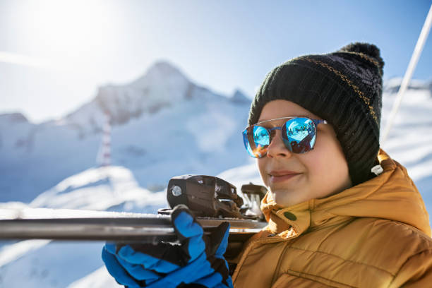porträt eines kleinen skifahrers, der seine skier trägt - ski resort hut snow winter stock-fotos und bilder