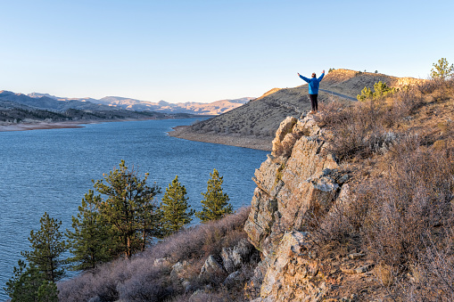 male hiker on a cliff overlooking Horsetooth Reservoir, popular recreation destination for boating, hiking and biking in northern Colorado, fall scenery