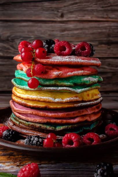 Colored pancakes with fruit, almonds and powdered sugar.