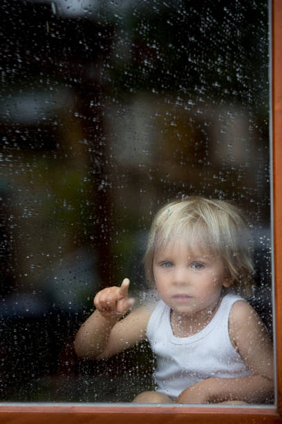 istock Sad child behind the window on rainy day 1285481804