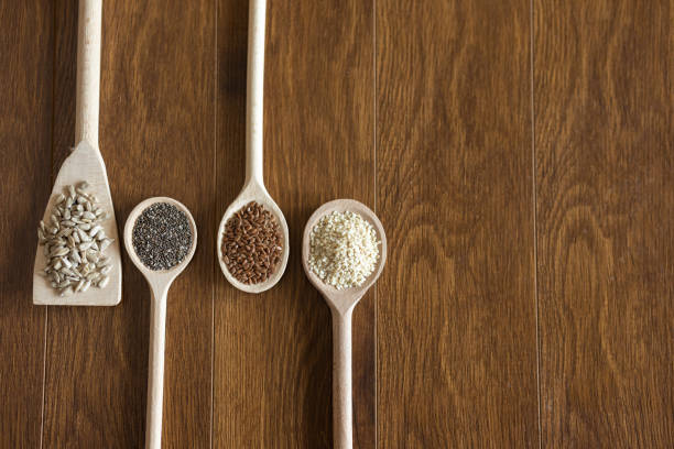 Wooden spoons with healthy seeds arranged on wooden table