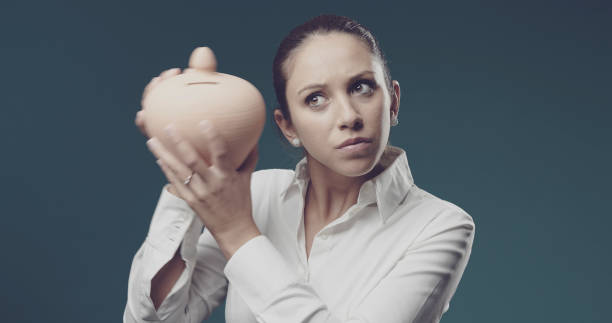 istock Woman shaking a money box and checking her savings 1285482942