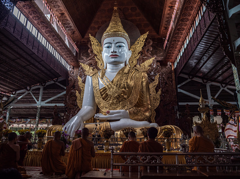 11/07/2019 Nga Htat Gyi Pagoda or the Sitting Buddha in Yangon, Myanmar.\nMonks praying in front of the big Buddha statue