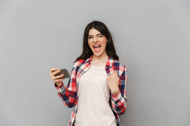 istock Emotional young lady play games by mobile phone make winner gesture. 1285485643