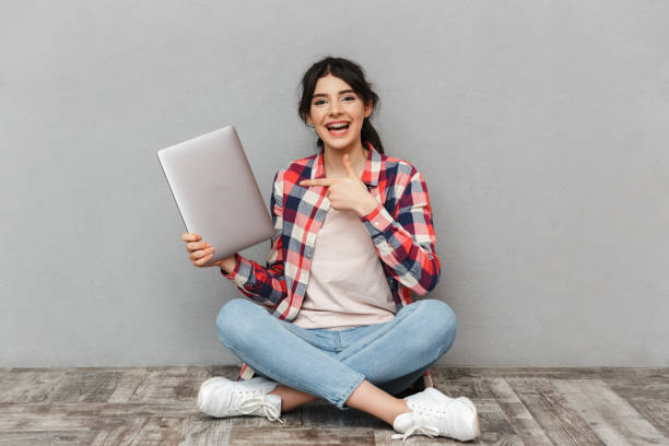 istock Happy young lady holding laptop computer pointing. 1285485705
