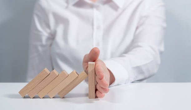 istock insurance, protection from wood-material by businesswoman’s hand, copy space, empty,blank area. Businesswoman Stop Domino Effect. Risk Management and Insurance, Businesswoman hand Stopping Falling wooden Dominoes. Business, Risk Management, domino effect 1285485814
