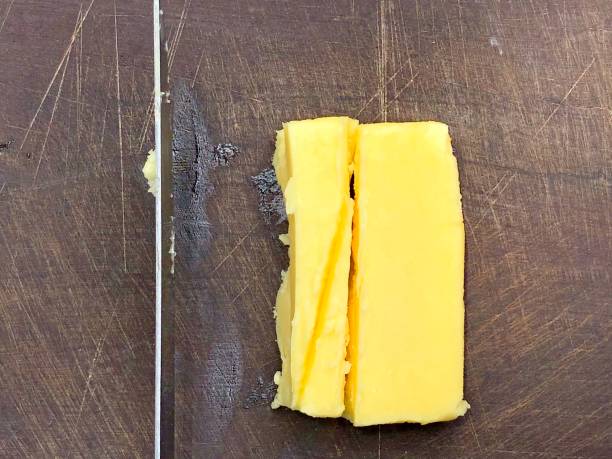 Cheese cutting down with knife in the wooden board.
