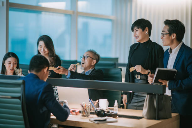 istock group of asian chinese white collar worker having a break during work late and taking snack at the workstation office place of work bonding 1285487480