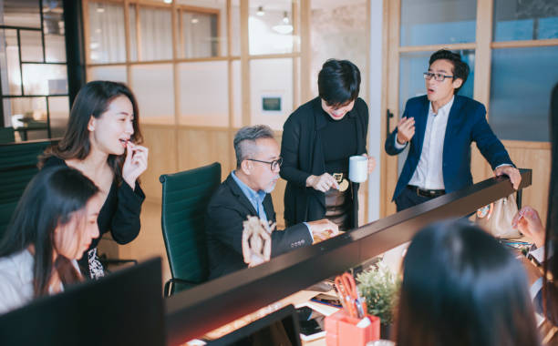 istock group of asian chinese white collar worker having a break during work late and taking snack at the workstation office place of work bonding 1285487598
