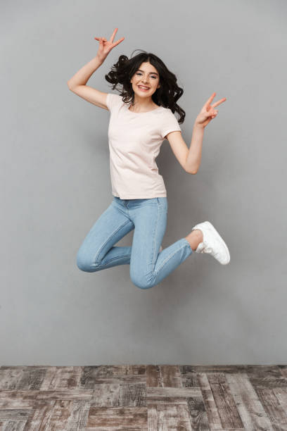 istock Pretty cute young lady jumping showing peace gesture. 1285489169