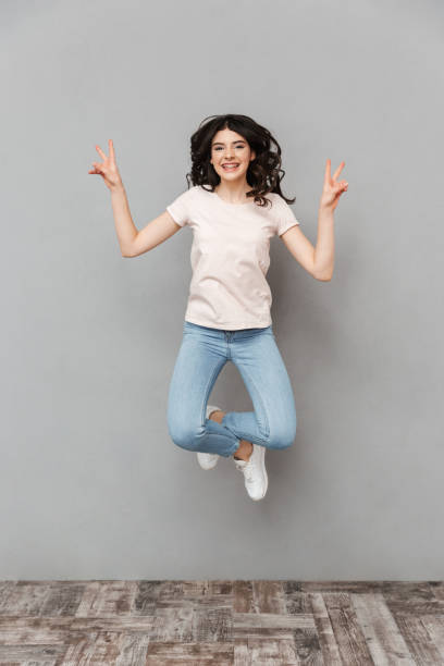 istock Pretty cute young lady jumping showing peace gesture. 1285489218