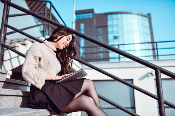 istock Cute Asian Female Using Digital Tablet While Sitting On Stairs 1285491078