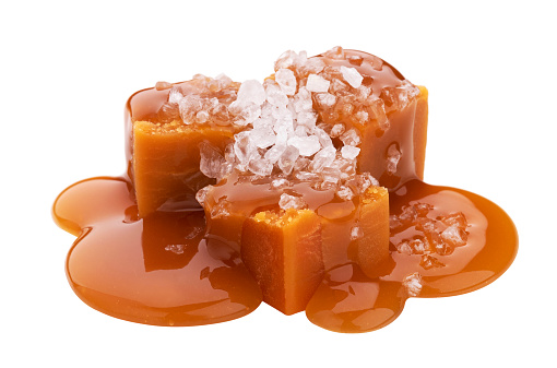 Toffee candies with melted caramel sauce and salt isolated on white background