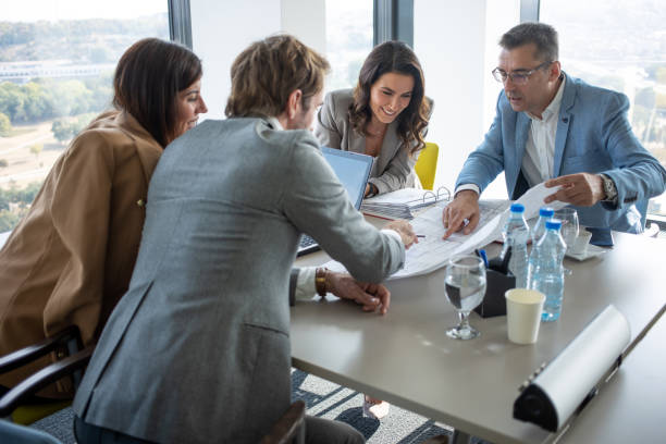 istock Colleagues looking at blueprints at the conference table 1285493618