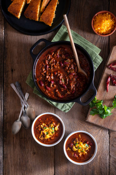 Chile Bowls of Homemade Chili with Corn Bread, Cilantro and Cheddar Cheese chili con carne stock pictures, royalty-free photos & images